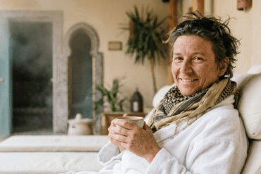 Traveler with a dusty desert scarf relaxing in a bathrobe and drinking herbal tea in a luxury spa after a desert safari in Hurghada.