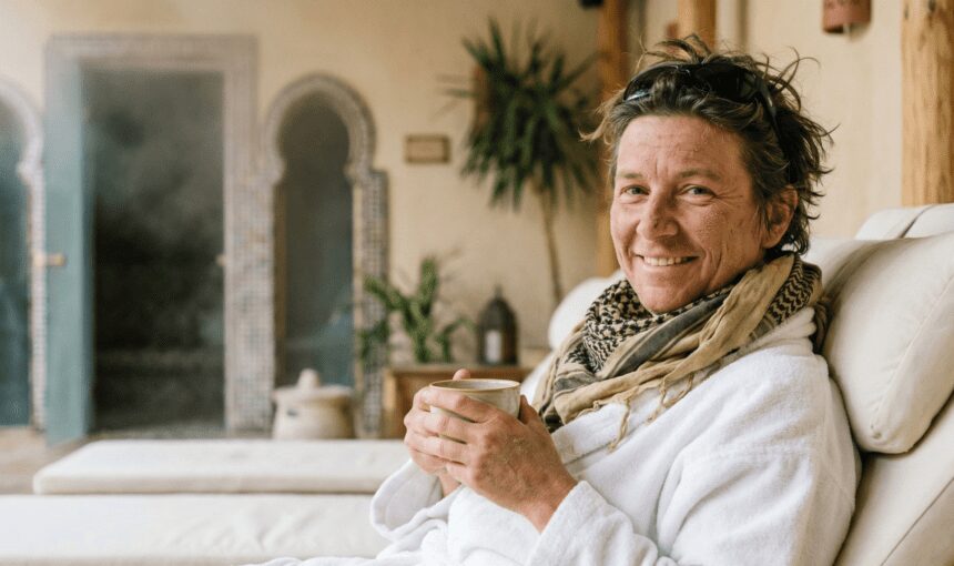 Traveler with a dusty desert scarf relaxing in a bathrobe and drinking herbal tea in a luxury spa after a desert safari in Hurghada.